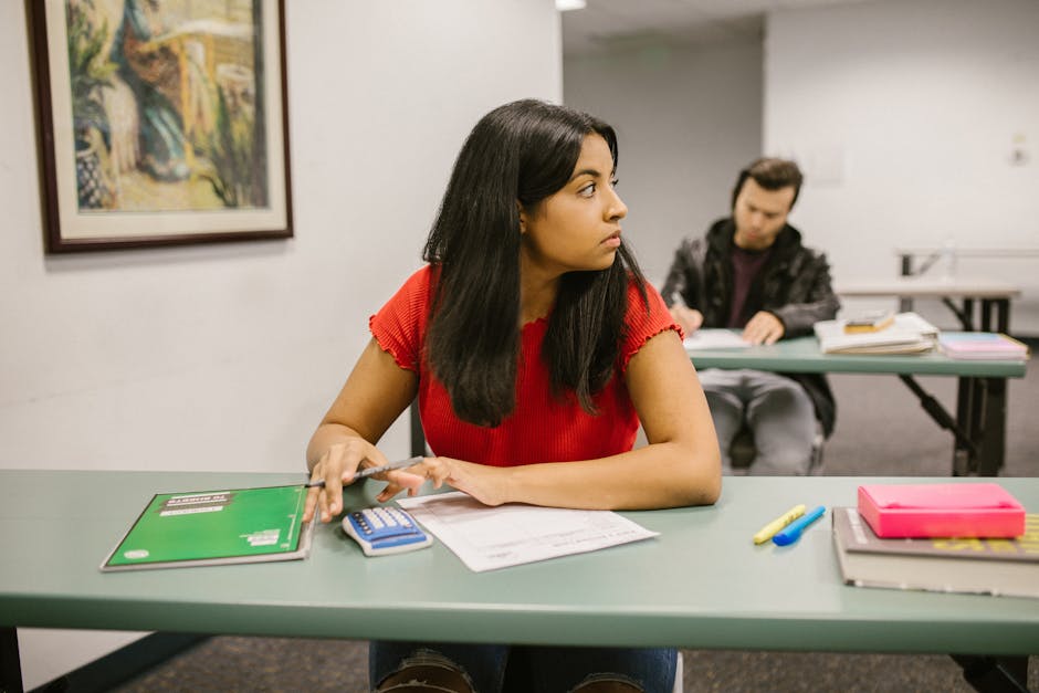 Students taking a test in a classroom, with one woman looking sideways. Education theme.