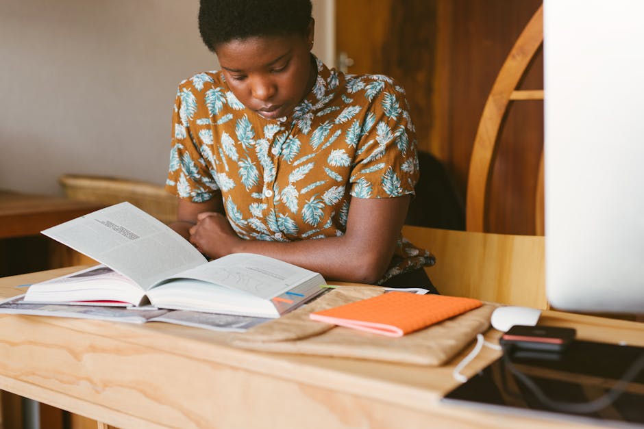 A young woman studies a book at her desk in a warm, indoor setting, illustrating a calm study environment