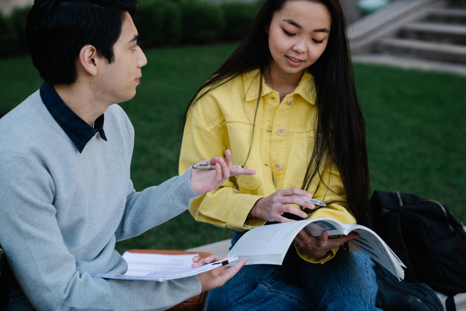 Two students engage in outdoor study session with textbooks and notes